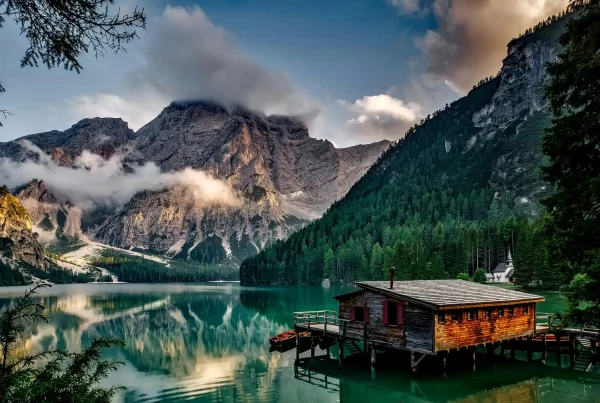 Mountain lake scene with a wooden cabin framed by trees, exemplifying framing in nature photography.